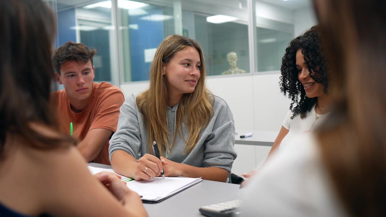 Gruppo eterogeneo di giovani studenti che collaborano e imparano in un'aula moderna.