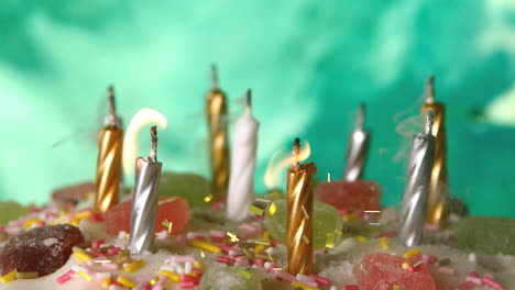 digital composition of golden confetti falling over burning candles on a cake