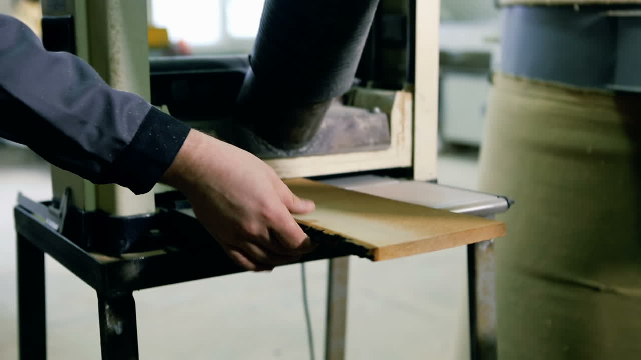 Electric Fret Saw For Cutting Wood. Hands of a skilled craftsman cutting a wooden plank with a saw in a workshop