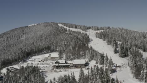 kope ski resort in slovenia at the pohorje mountains with people skiing down the ribnica one track, aerial pan right shot