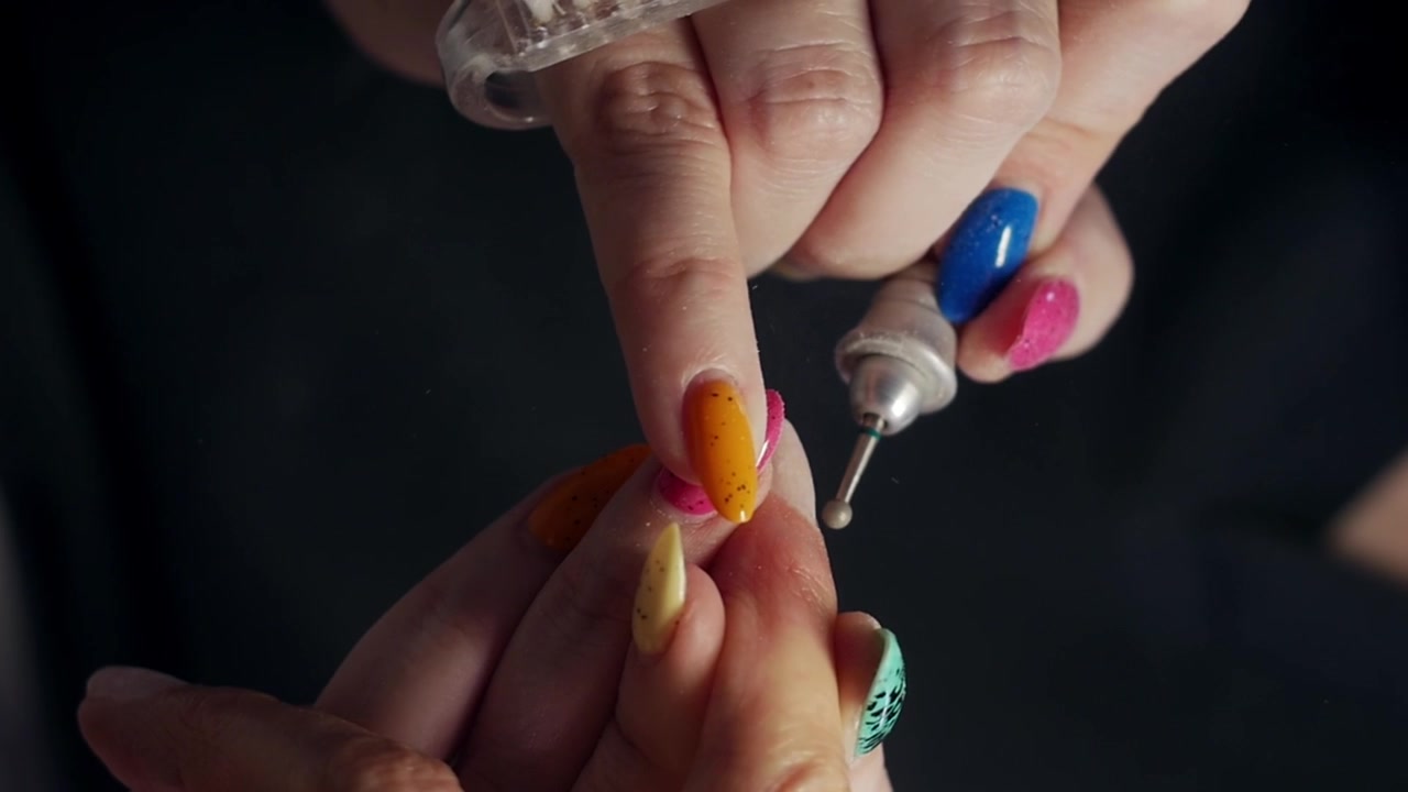 Beautician removing nail polish with electric nail drill