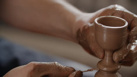 hands shaping a clay cup