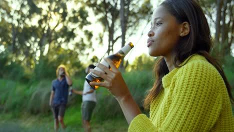 thoughtful young woman drinking beer in the forest 4k