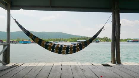 Empty-rope-hammock-hanging-between-trees-on-sandy-tropical-island-beach-on-a-sunny-cloudy-day-in-Hawaii