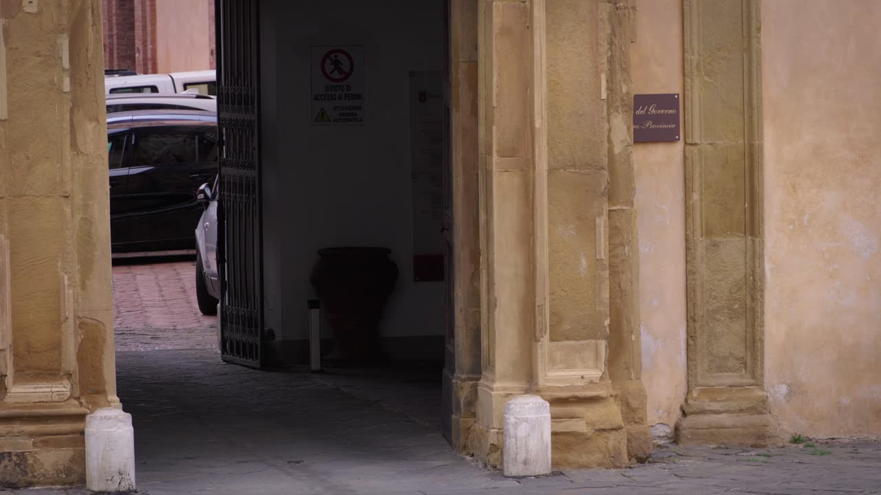 A police officer walks past historic stone arches in Tuscany, Italy