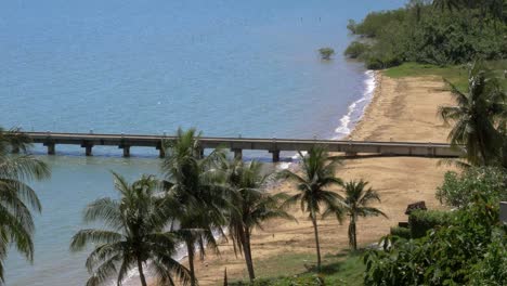 una isla bahía, palmeras y un muelle con pequeñas olas