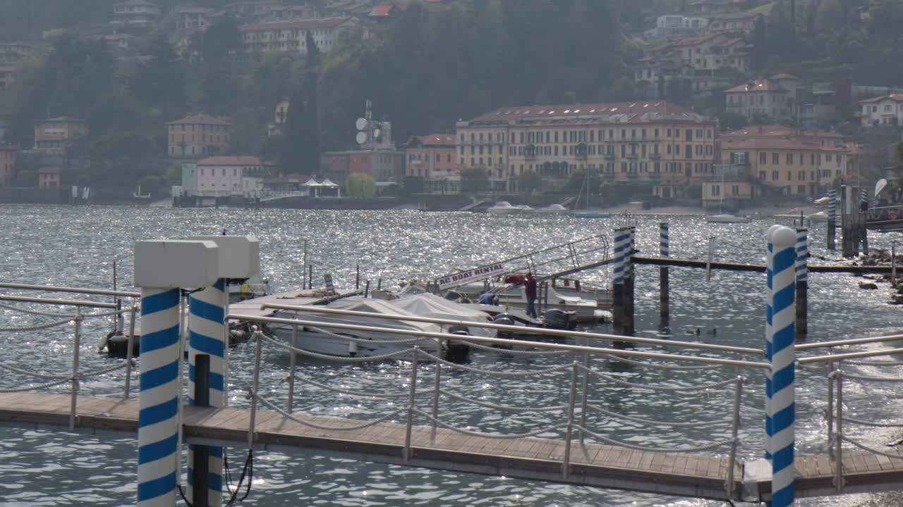 Boats Moored In The Jetty In Lake Como In Menaggio, Como, Lombardy, northern Italy. - wide shot