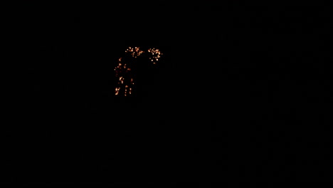 Slow motion burning embers that glow and emit sparks as it lowly burns out.