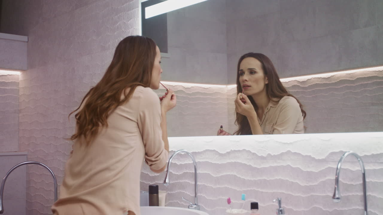 Donna d'affari che si trucca in bagno. Bella donna che si guarda allo specchio