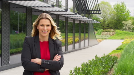 portrait of smiling mature businesswoman standing outside modern office building