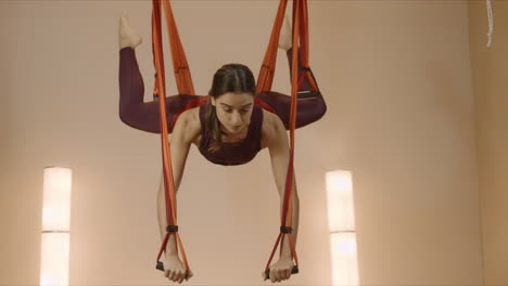 woman doing split in hammock at class. sportswoman practicing antigravity yoga