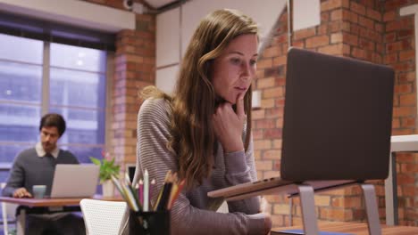 Creative-businesswoman-using-laptop-in-modern-office