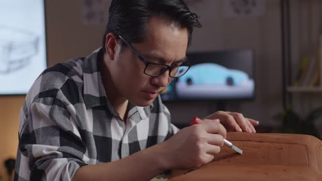 close up of asian man automotive designer celebrating success working on the sculpture of car clay by rake or wire in the studio