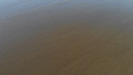 waves moving across dark sand in bali on the west coast