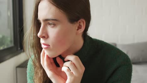 Caucasian-non-binary-transgender-woman-sitting-on-bed-and-thinking