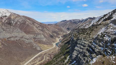 Excelente-Toma-Aérea-De-Autos-Conduciendo-Por-Un-Camino-Delgado-Entre-Picos-De-Montaña