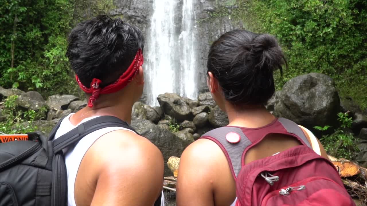 пара любуется высоким водопадом, когда камера движется к ним сзади в замедленной съемке