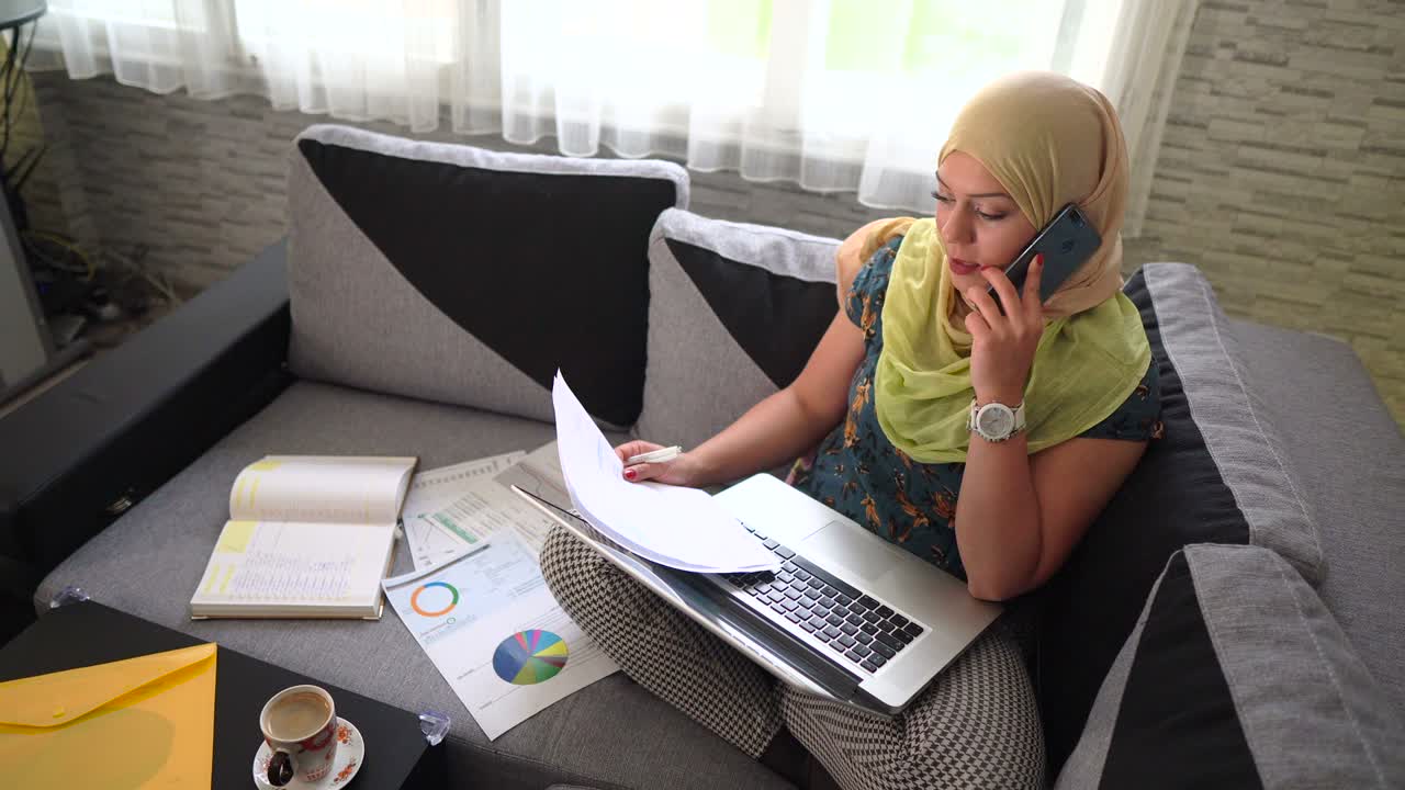 Ung muslimsk kvinde iført hijab, der arbejder og bruger bærbar computer.