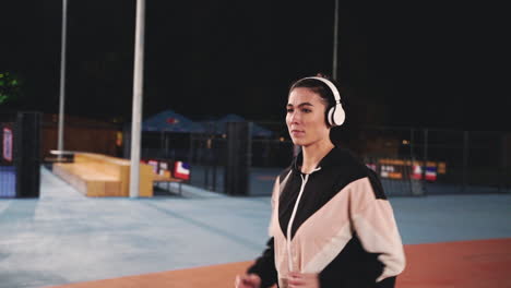 Sportive-Sportswoman-Using-Bluetooth-Headphones-Running-In-The-Park-At-Night-1
