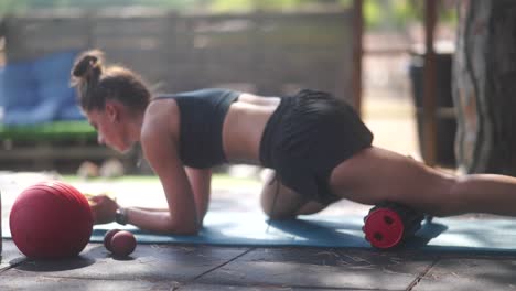 woman doing outdoor stretching exercises with foam roller and exercise ball