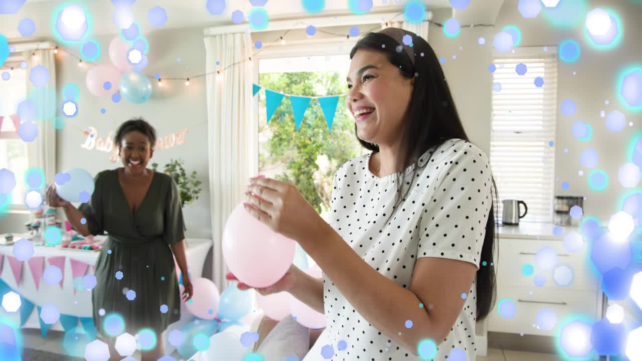 Polka-dot woman starting inflating pink balloon, friend inflating blue balloon, prepping party