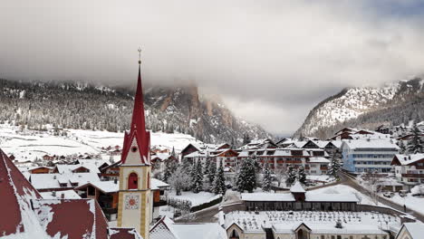 snowy town with church steeple in selva di val gardena, italy