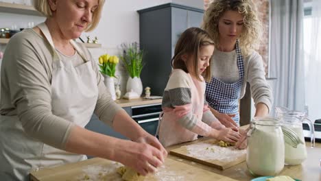 video of three generations of women kneading dough in kitchen