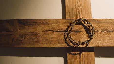 concepto religioso filmado con corona de espinas y cruz de madera en un charco de luz 1