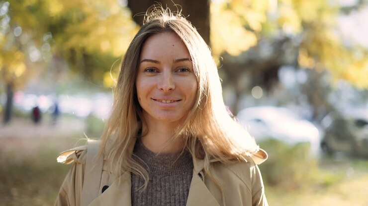 Ritratto di donna sorridente all'aperto con bagliori dell'obiettivo in autunno.