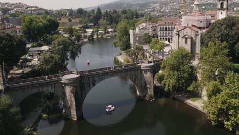 Swan-boat-sailing-under-historical-castle-bridge-in-Amarante-town,-Portugal
