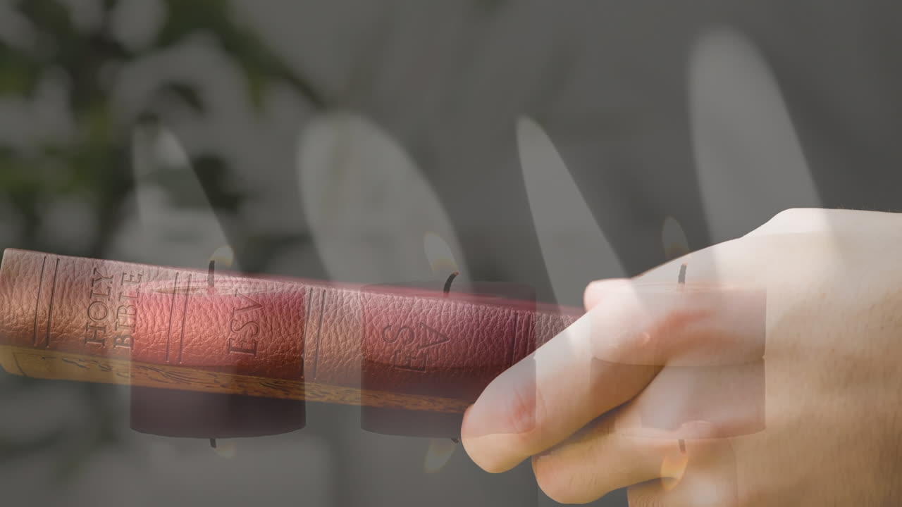 성경을 들고 있는 손의 클로즈업에 대한 불타는 불의 복합 비디오