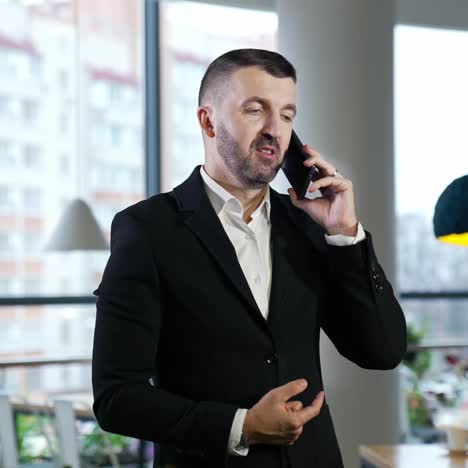 businessman having a pleasant conversation on the mobile phone. confident man has business talk on the phone. big windows at the backdrop
