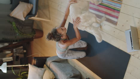 woman practicing yoga at home with her dog