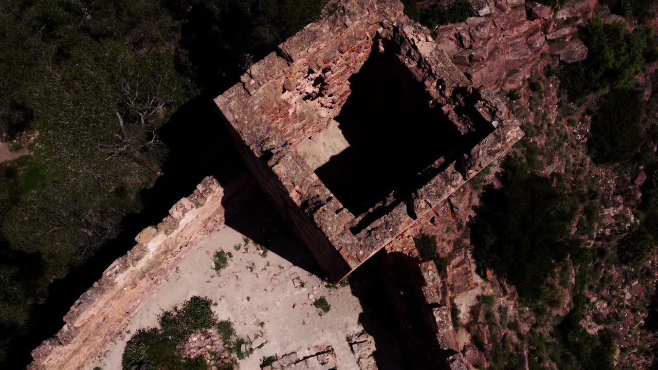 4K drone overhead shot (top-down) of the ancient Serra Castle ruins, showcasing the internal defensive structure and exposed foundation stone in Serra, Valencia, Spain, on a sunny day