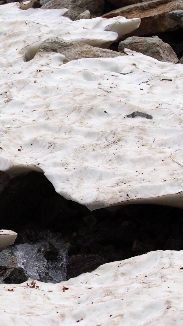 Primo piano dello scioglimento della neve primaverile che scorre sulle rocce al Lago della Rovina, Entracque, Italia.