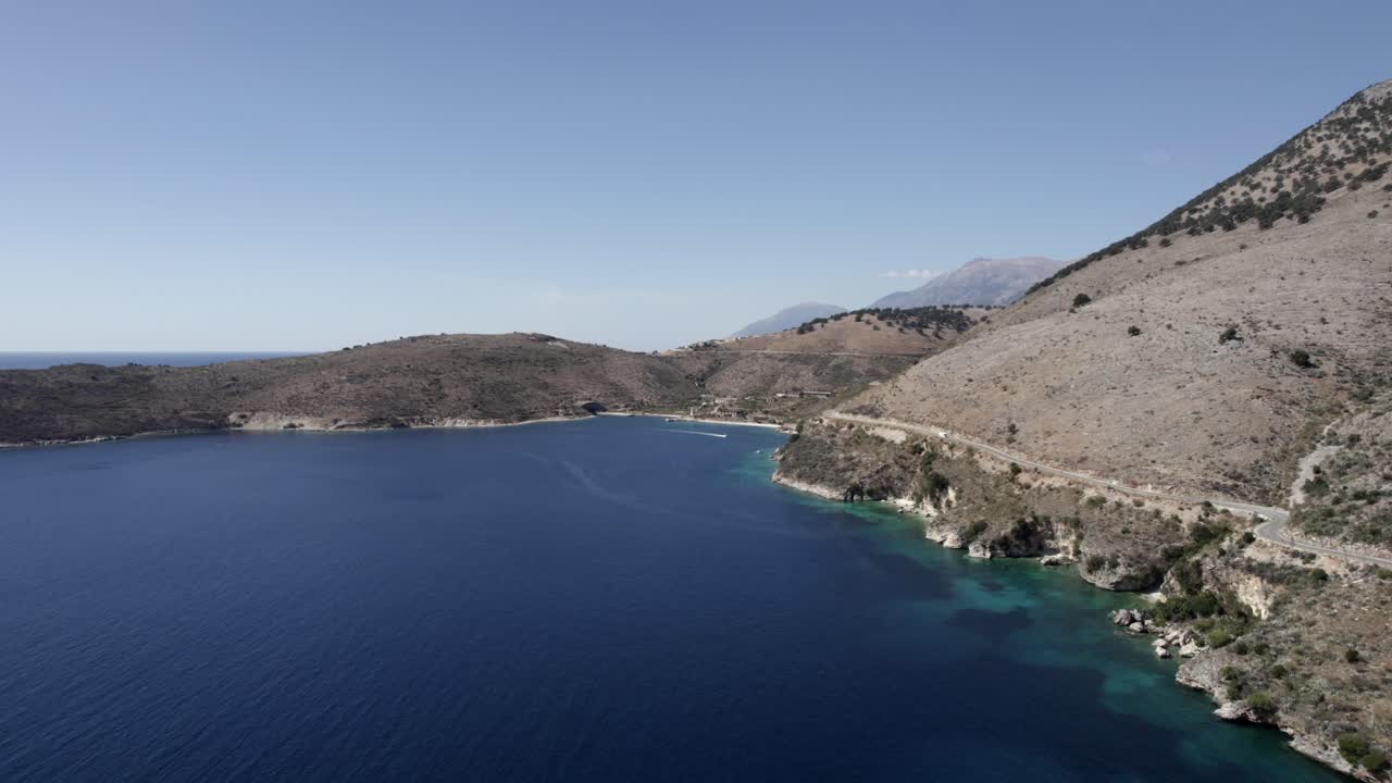 Drone video over the turquoise waters of the Albanian coast in Porto Palermo, you can see a submarine Bunker from the Second World War and a boat sailing