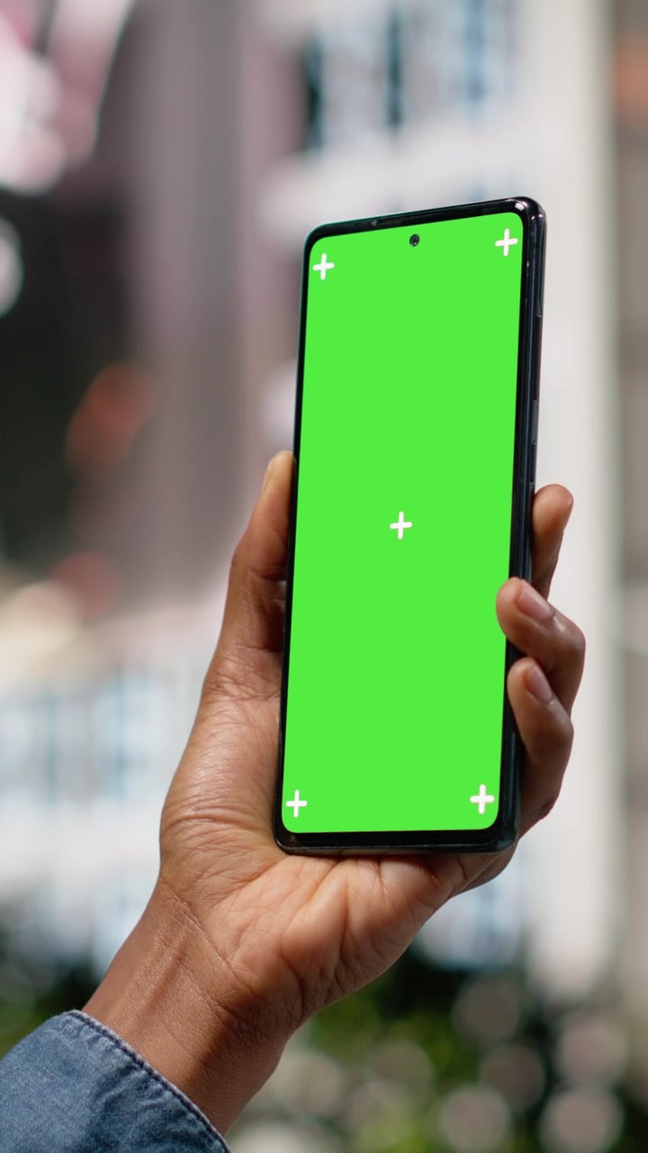Video verticale: smartphone verticale con schermo verde, con donna afroamericana su una panchina in un'area metropolitana.