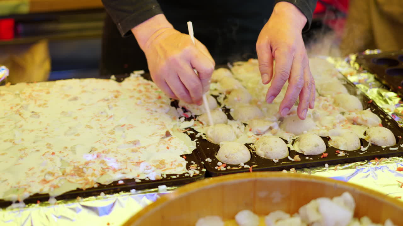 Close up of squid dumplings being cooked on a cast iron takoyaki grill pan at a street food market in Japan