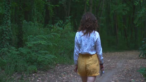 a young woman passing through with an old film camera in her hands, shot from her back