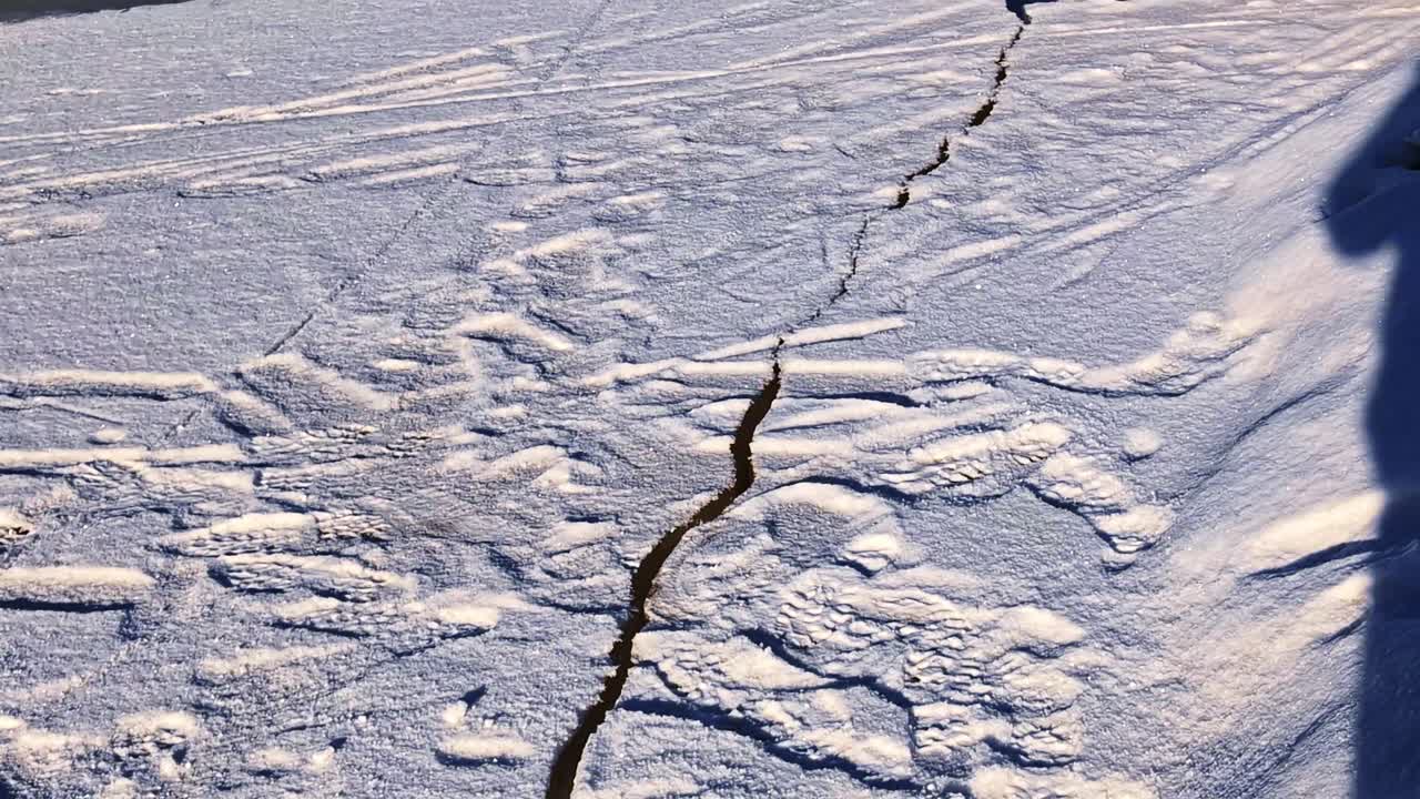 Smeltende isflak som sprekker opp på en rennende blå elv om vinteren.