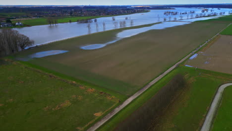 Drone-Inclinado-Hacia-Arriba-Desde-El-Campo-Y-La-Pradera-Hasta-El-Paisaje-De-La-Llanura-Aluvial-Del-Río-Mosa