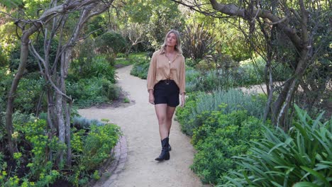 Young-woman-walks-through-wooden-archway-in-garden-and-spins