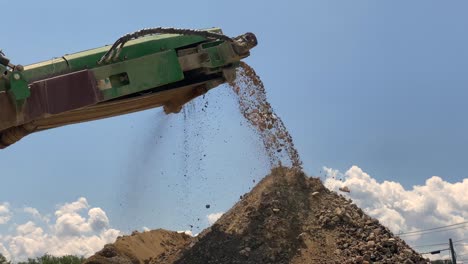 crushed rocks and concrete coming off the belt of a rock crusher