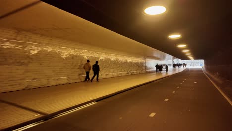 people walking through a city tunnel at night