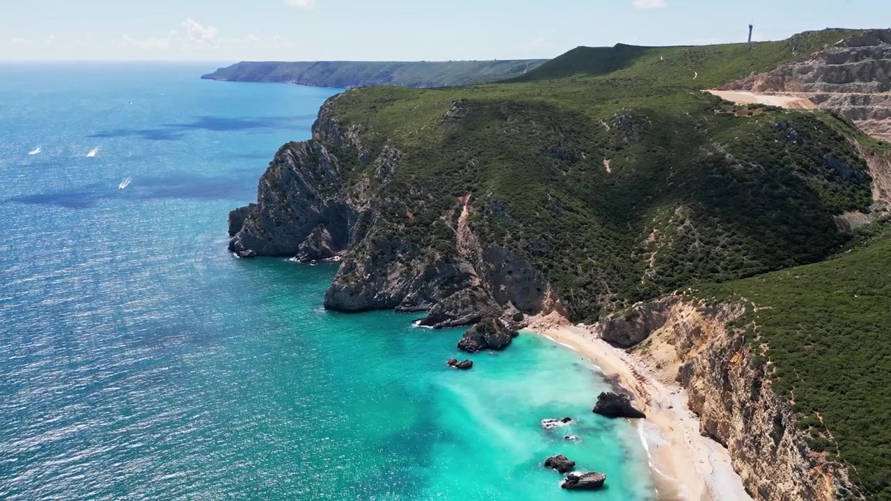 Vista aerea di acqua turchese e scogliere frastagliate lungo una spiaggia sabbiosa isolata