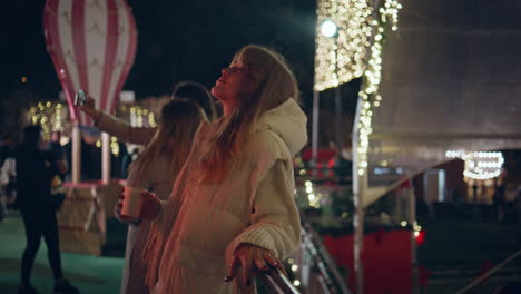 girl relaxing festive fair at night holding hot beverage. woman standing street