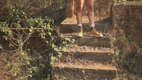 legs of a young brunette girl in yellow boots on some concrete steps in a country area