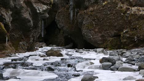 a river flowing over snow and ice covered rocks as it leaves a ravine