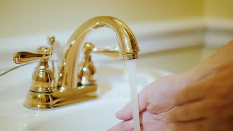 un hombre se lava las manos bajo un grifo con agua