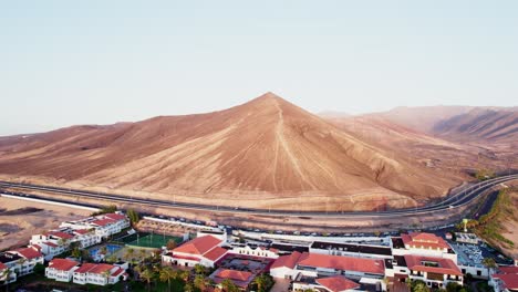 quaint town nestled at the base of a majestic mountain in fuerteventura, clear skies, aerial view